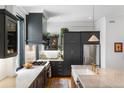 Modern kitchen with dark cabinetry, stainless steel appliances, and marble countertops at 3424 W 31St Ave, Denver, CO 80211