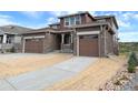 Front of a home with a three-car garage, stone accents, and a covered porch at 3979 Descent St, Castle Rock, CO 80108