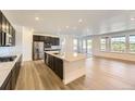 Open-concept kitchen with stainless steel appliances, quartz island, dark cabinetry and hardwood flooring at 3979 Descent St, Castle Rock, CO 80108