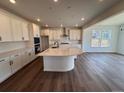 Bright kitchen features a large island, modern appliances, white cabinets, and wood-look flooring at 283 Wooten Ave, Brighton, CO 80601