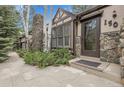 Close-up of home's entry, highlighting the stone facade, Tudor detailing, and the front door with glass window at 150 Soda Creek Rd, Evergreen, CO 80439
