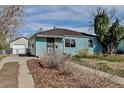 Quaint home with light blue siding and a detached garage showcases its classic charm and functional outdoor space at 1108 Roslyn St, Denver, CO 80220