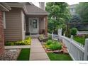 Charming home featuring a cozy front porch with decorative landscaping and a white picket fence at 9864 Carmel Ct, Lone Tree, CO 80124