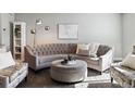 Elegant living room with tufted sofa, ottoman, stylish decor, and plenty of natural light at 9612 Reunion Pkwy, Commerce City, CO 80022
