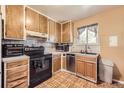 Cozy kitchen featuring wooden cabinetry, black appliances, and a window above the sink at 11816 Spring Dr, Northglenn, CO 80233