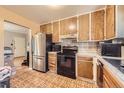 Functional kitchen showcasing wooden cabinets, a stainless steel refrigerator, and a compact layout at 11816 Spring Dr, Northglenn, CO 80233