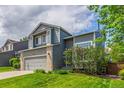 Two-story home with gray siding, a two-car garage, and a manicured lawn featuring lush bushes at 4935 Apollo Bay Dr, Highlands Ranch, CO 80130