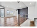Bright and airy living room featuring hardwood floors, large windows, and a decorative accent wall at 5128 Preserve Pl, Firestone, CO 80504