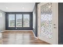 Bright living room with accent wall, hardwood floors, and decorative glass door at 5128 Preserve Pl, Firestone, CO 80504
