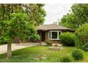 Quaint brick home with mature trees, landscaped lawn, and a cozy front porch at 654 S Shoshone St, Denver, CO 80223