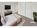 Cozy bedroom with a wooden bed frame, flat-screen TV, and a double-door closet, virtually staged at 1045 Mobile St, Aurora, CO 80011