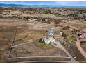 Expansive aerial view showcasing the home's location on a large lot with white fencing and mountain views at 595 W Oak Hill Ln, Castle Rock, CO 80108