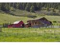 Image of red barn and wooden barn in a grassy field at 15947 S Perry Park Rd, Palmer Lake, CO 80133