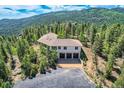 Exterior of home with three-car garage nestled among trees with mountain views at 30671 Bearcat Trl, Conifer, CO 80433