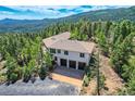 Exterior of home with three-car garage nestled among trees with mountain views at 30671 Bearcat Trl, Conifer, CO 80433