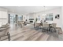 Open-concept living room featuring modern fireplace, hardwood floors, dining area, and a sliding glass door at 7051 S White Crow Way, Aurora, CO 80016