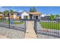 Charming home with a black fence, modern rock landscaping, and synthetic turf at 3064 S Galapago St, Englewood, CO 80110