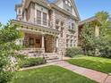 Charming stone home showcasing a well-manicured lawn, covered porch, and mature landscaping at 1453 Vine St, Denver, CO 80206