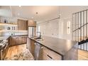 Modern kitchen features a large center island with stone countertop, stainless steel appliances, and custom wood cabinetry at 2378 S Bannock St, Denver, CO 80223