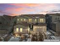 Charming two-story home with stone accents, three car garage, and picturesque landscaping against a colorful sunset sky at 6922 Copper Sky Cir, Castle Pines, CO 80108