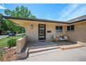 Inviting front porch with seating, a modern door, and brick accents, perfect for enjoying the outdoors at 6987 E Wyoming Pl, Denver, CO 80224
