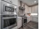 Modern kitchen with stainless steel appliances, gray cabinetry, tile backsplash, and wood flooring at 21935 E 51St Dr, Aurora, CO 80019