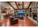 Cozy living room with hardwood floors, a stone fireplace, beamed ceilings and large glass doors with view of the mountains at 10693 Mountaingate Ct, Highlands Ranch, CO 80126