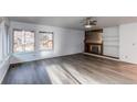 Spacious living room featuring a fireplace, built-in shelving, large windows, and modern gray woodgrain flooring at 53 S Eagle Cir, Aurora, CO 80012
