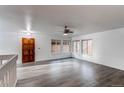 Open living area with dark wood door, gray woodgrain floors, and large windows for natural light at 53 S Eagle Cir, Aurora, CO 80012