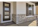 Close up of the front porch showing the stone detail, front door with frosted windows, and dark shutters at 2962 Newfound Lake Rd, Berthoud, CO 80513