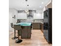 Modern kitchen with unique glass-topped island, breakfast bar seating, stainless steel appliances and hardwood floors at 3295 Blake St # 102, Denver, CO 80205
