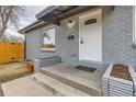 A covered porch with gray brick planters, leading to a white front door of this charming home at 9295 E 12Th Ave, Aurora, CO 80010