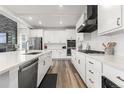 Modern kitchen with white cabinets, stainless steel appliances, quartz countertops, and a sleek black range hood at 17121 Desert Wine Ln, Parker, CO 80134