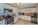 Well-lit kitchen featuring white cabinets, granite countertops, stainless steel appliances, and tile flooring at 3148 Victor St, Aurora, CO 80011