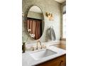 Stylish bathroom with floral wallpaper, a round mirror, marble countertop, and decorative light fixture at 3445 S Clermont St, Denver, CO 80222
