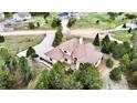 An aerial shot showcasing a house with a concrete driveway and a well-maintained yard surrounded by lush trees at 1120 Brenthaven Ct, Monument, CO 80132