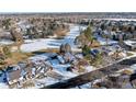 Aerial view of home with mature trees and snow-covered yard and golf course in the background at 78 Fairway Ln, Littleton, CO 80123