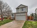 Charming gray two-story home with a well-manicured lawn, brick accents, and attached two-car garage at 378 Benton St, Castle Rock, CO 80104