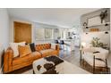 Cozy living room featuring a tufted leather sofa, stylish ottoman, and an open layout to the kitchen at 1349 Race St # 5, Denver, CO 80206