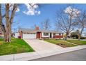 Street view of a red brick single-story home with an attached two car garage and a well-maintained lawn at 13373 W 24Th Pl, Golden, CO 80401