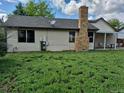 Home backyard featuring a large yard, brick chimney, and covered patio area at 16094 E Exposition Dr, Aurora, CO 80017