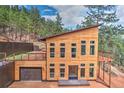 Striking contemporary home with light wood siding, large windows, garage, upper deck and a private treed lot at 15175 Rainbow Dr, Sedalia, CO 80135