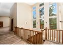 Upper hallway with a wood railing, wood floor, neutral walls and large windows offering a scenic view at 15175 Rainbow Dr, Sedalia, CO 80135