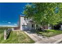 A well-maintained two-story home featuring a lush green lawn and mature trees at 1353 Mallard Ln, Brighton, CO 80601