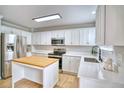 Bright kitchen with stainless steel appliances, white cabinets, an island, and quartz countertops at 5532 S Valdai Way, Aurora, CO 80015