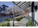 Inviting front porch with black metal awning, mature landscaping, and neighborhood views at 1825 W 32Nd Ave, Denver, CO 80211