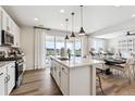 Modern kitchen featuring white cabinets, stainless appliances, and an island with pendant lighting at 104 Wooten Ave, Brighton, CO 80601