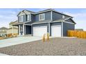 Two-story home featuring a three-car garage, wood siding, and rocky front yard at 562 Twilight Ct, Fort Lupton, CO 80621