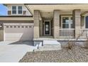 Close up of the home's front porch with brick columns, storm door, and two-car garage at 6172 N Liverpool St, Aurora, CO 80019