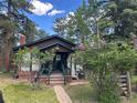Inviting cabin with a quaint front porch and lush greenery, creating a serene atmosphere at 4393 Pima Rd, Indian Hills, CO 80454